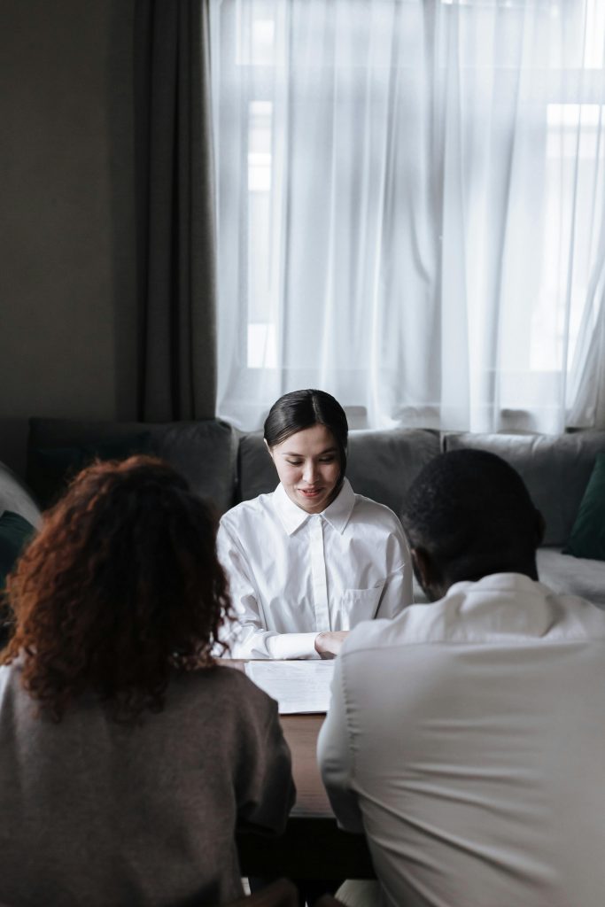 pexels-photo-9870134-9870134 A diverse group meeting with a social worker in a cozy home setting, discussing important documents.